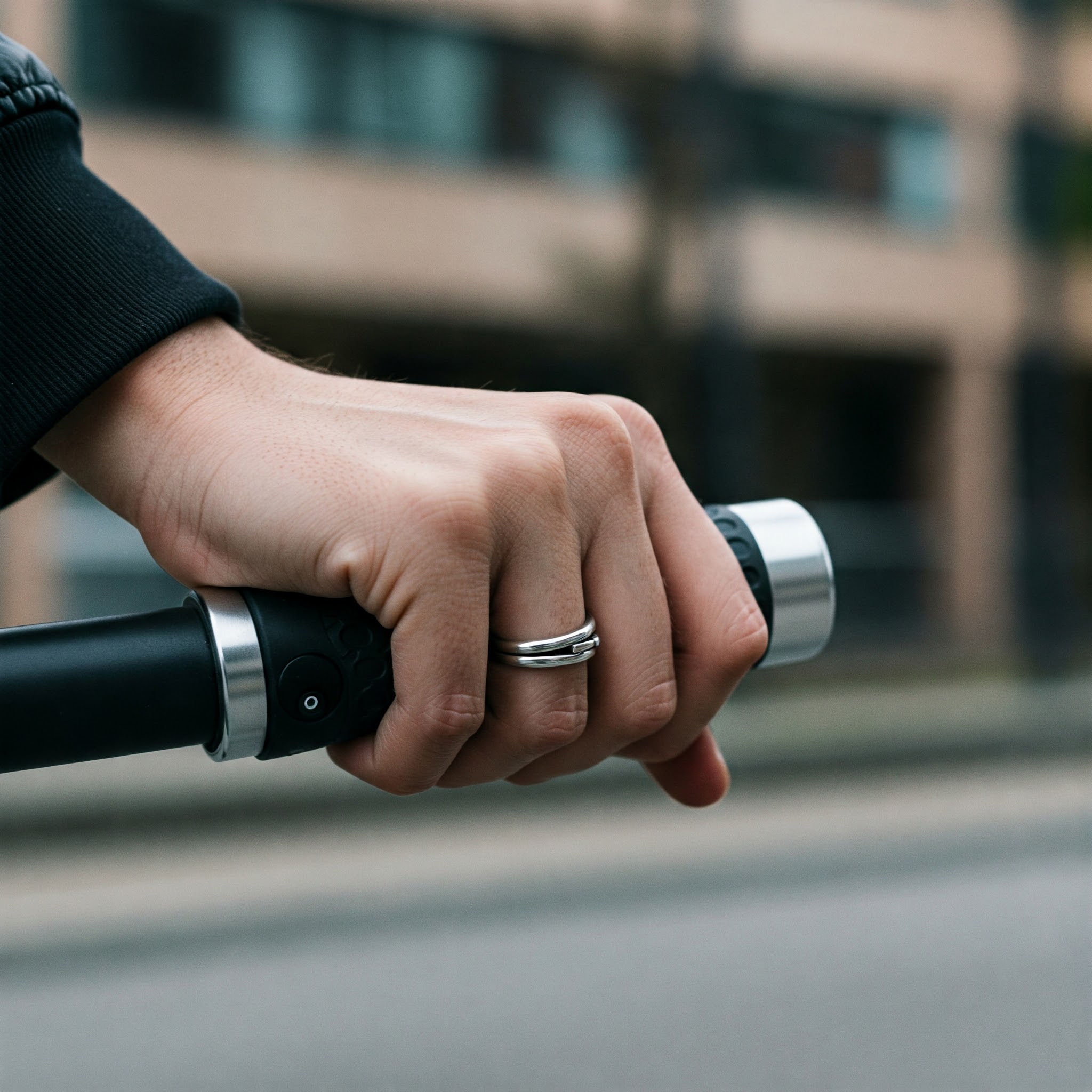 Hand gripping the electric scooter throttle for speed control.